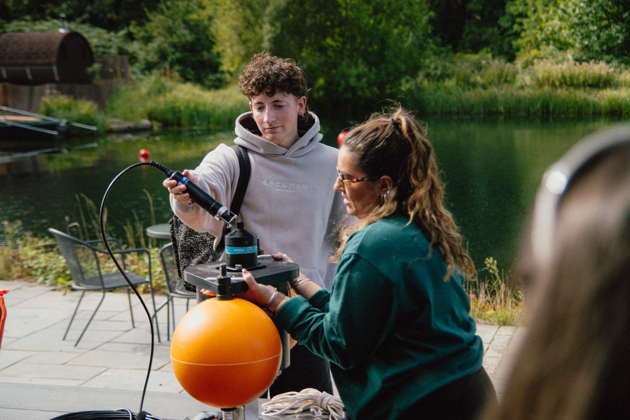 A student tests an acoustic receiver by a lake